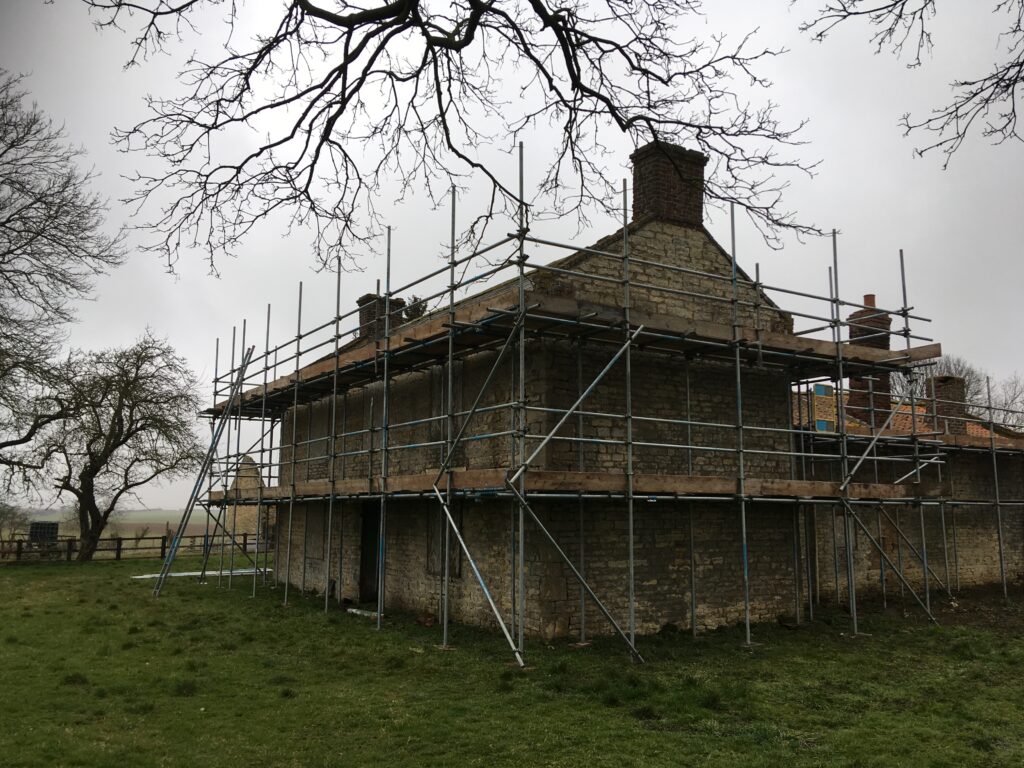 scaffolding surrounding an old farm house - image 6