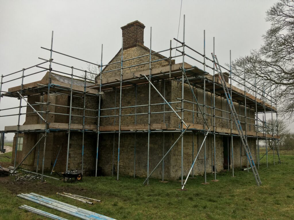 scaffolding surrounding an old farm house - image 5