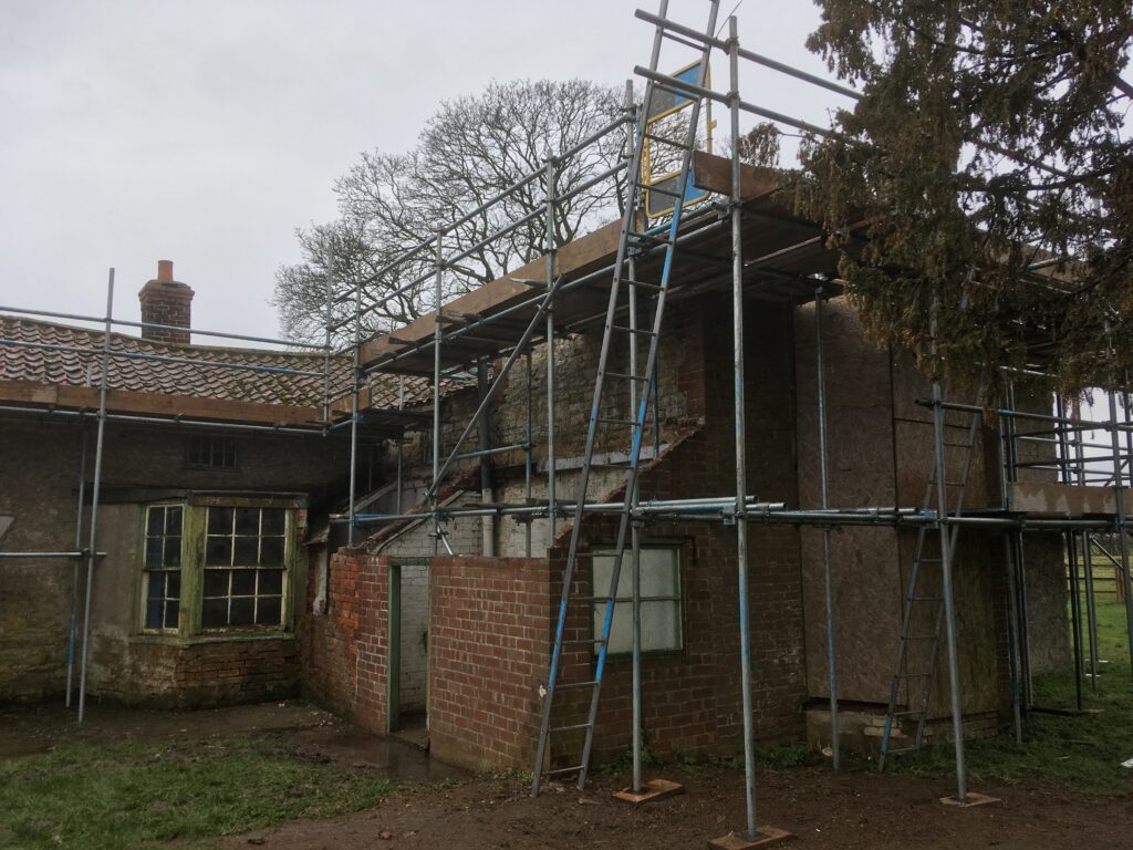 scaffolding surrounding an old farm house - image 2