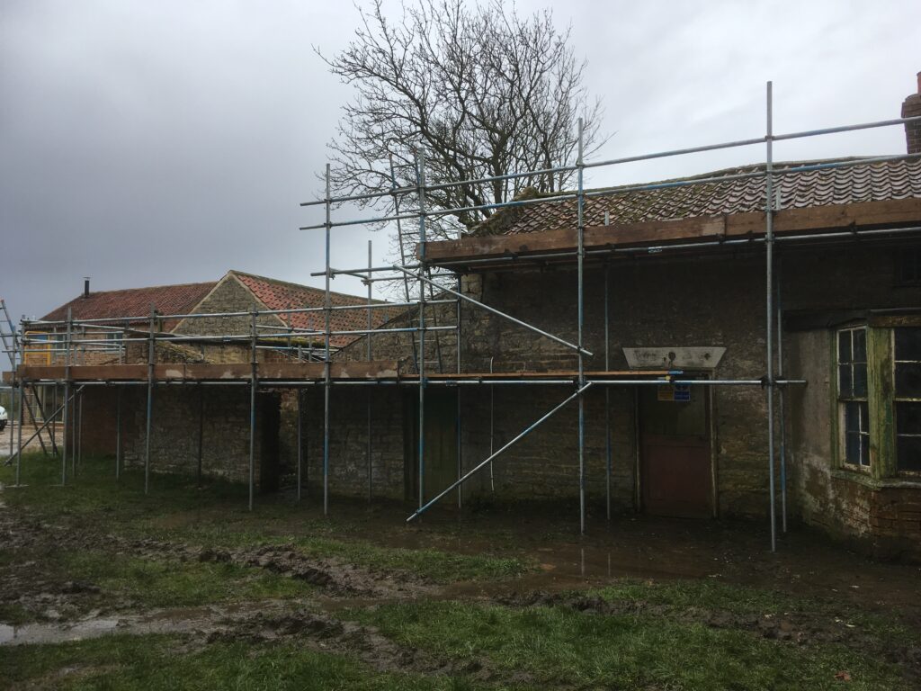 scaffolding surrounding an old farm house