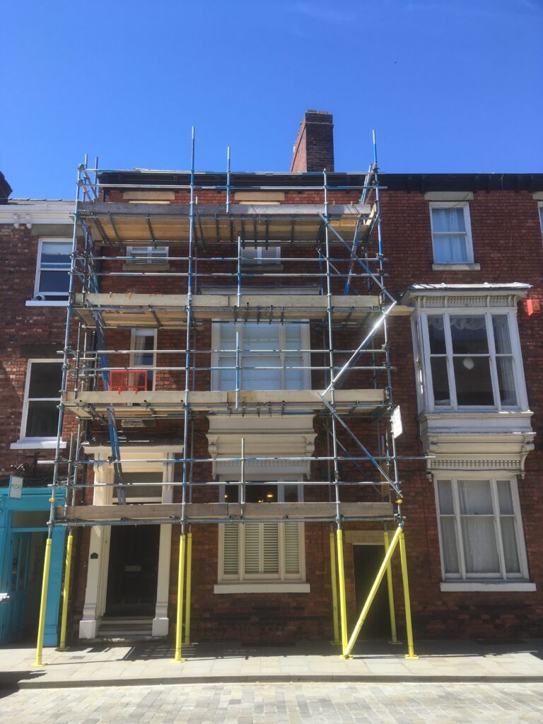scaffolding on the front of terraced house with pavement underneath
