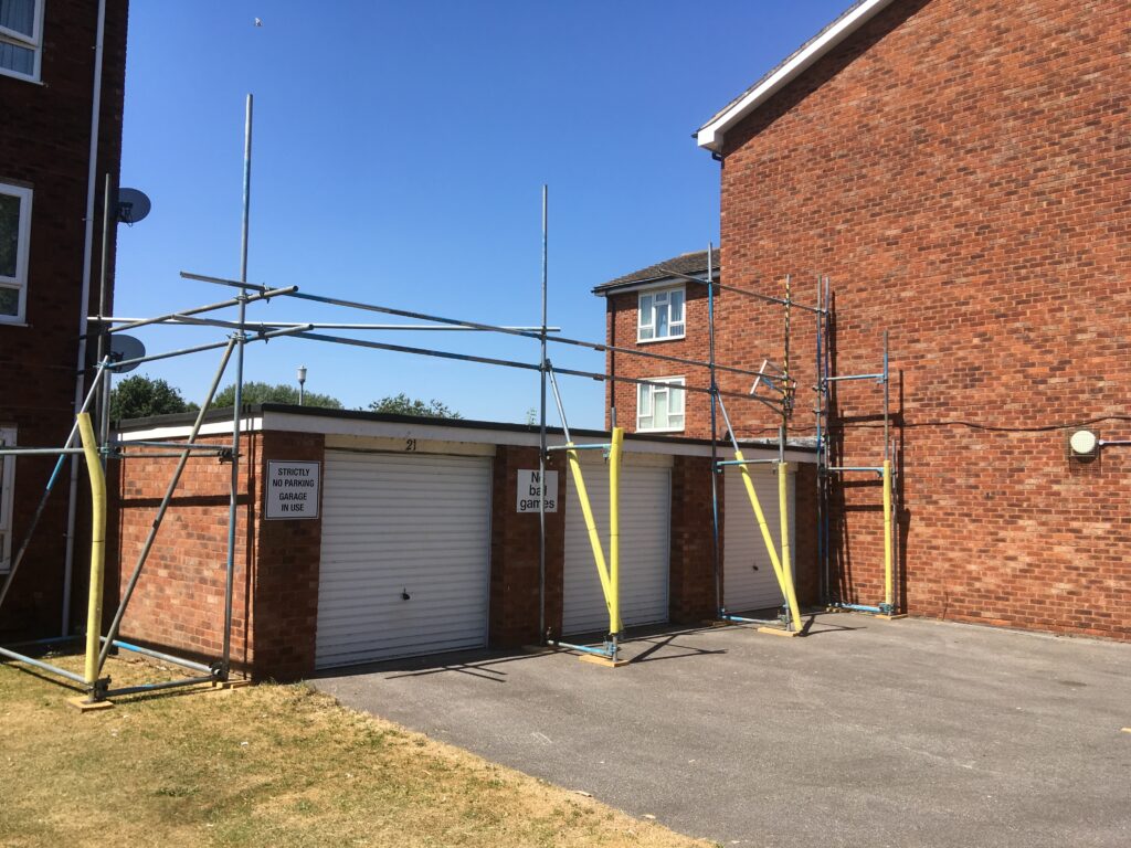 scaffolding surrounding some flat block garages