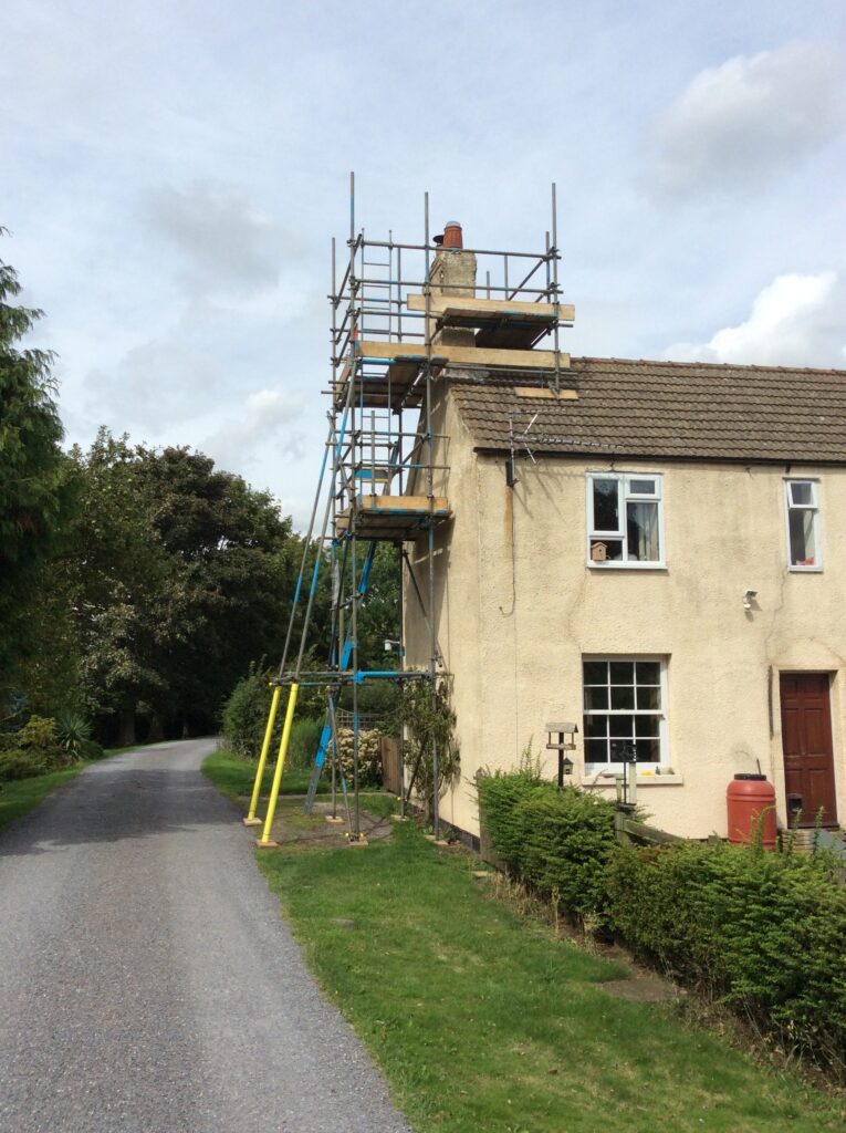 scaffold tower on side of cottage by road