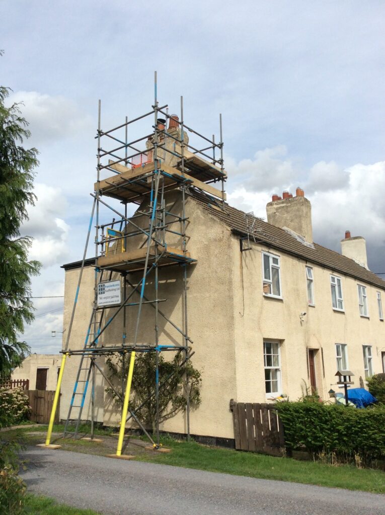 scaffold tower on side of cottage by road - image 2