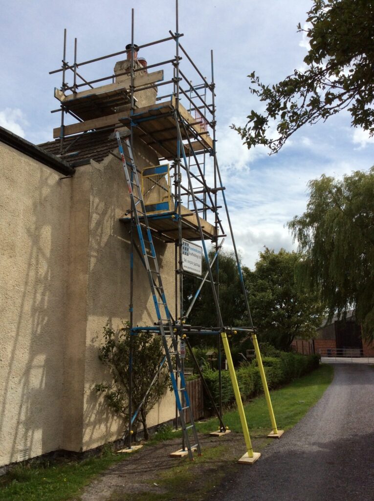 scaffold tower on side of cottage by road - image 4