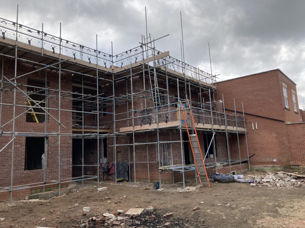Scaffolding surrounding two multi-story houses from top to bottom, providing access for easier construction - image 7