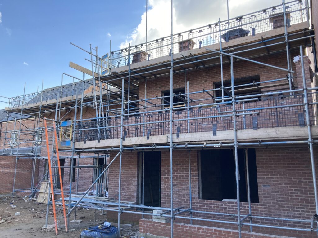 Scaffolding surrounding two multi-story houses from top to bottom, providing access for easier construction - image 5