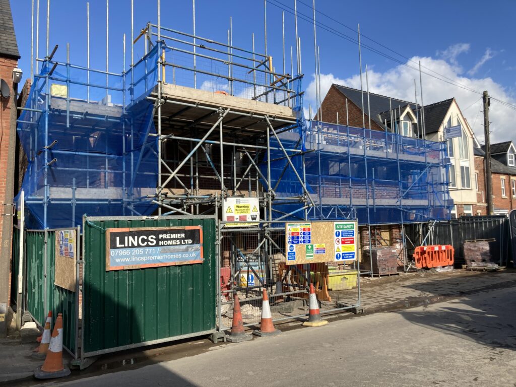 Scaffolding surrounding two multi-story houses from top to bottom, providing access for easier construction - image 4