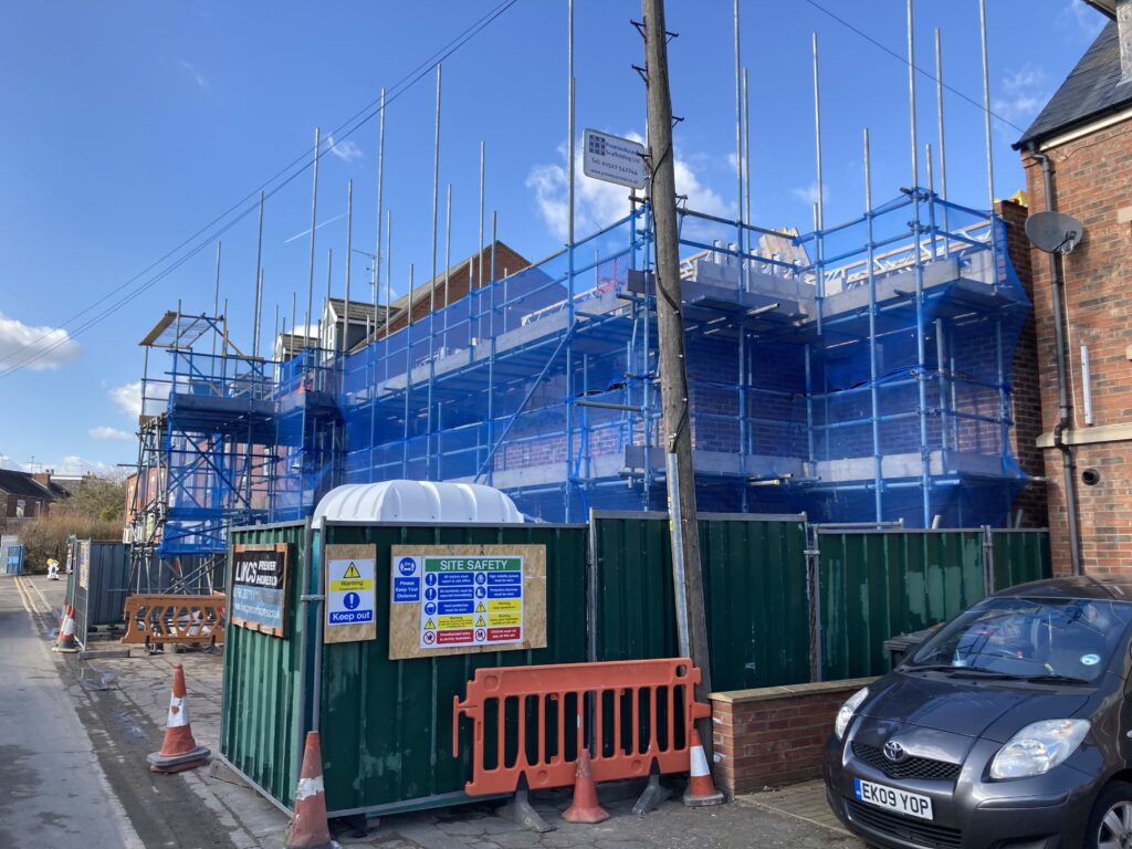 Scaffolding surrounding two multi-story houses from top to bottom, providing access for easier construction - image 3