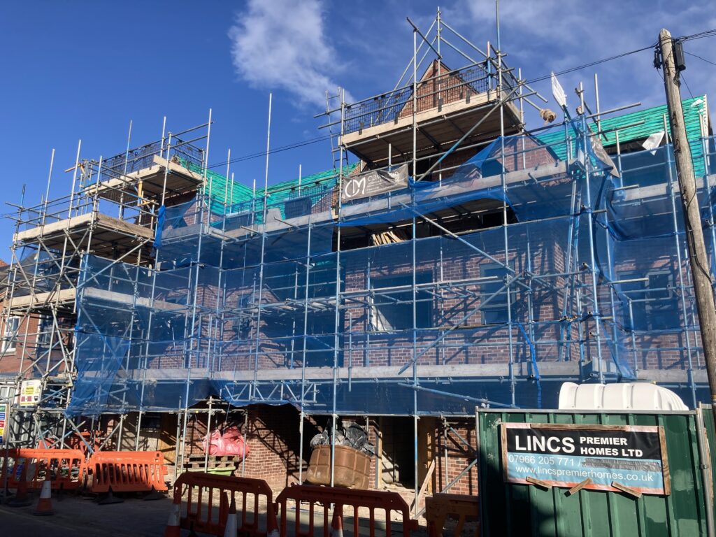 Scaffolding surrounding two multi-story houses from top to bottom, providing access for easier construction - image 2
