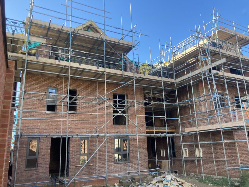 Scaffolding surrounding two multi-story houses from top to bottom, providing access for easier construction