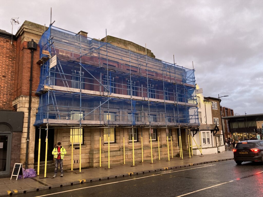 scaffolding on the front of a building by a busy road in Lincoln