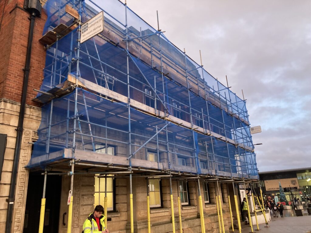 scaffolding on a building by a busy road in Lincoln