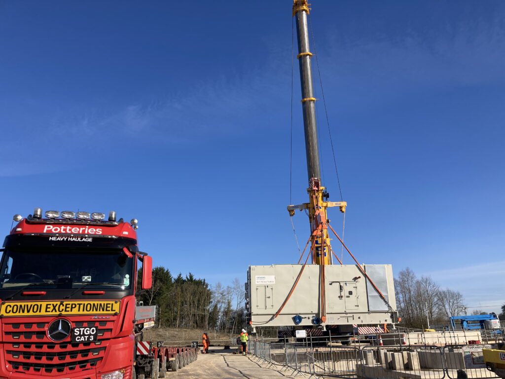 a crane lifting a gas turbine off a lorry for installation