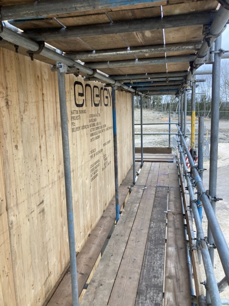 scaffolding surrounding a covered gas compressor on a construction site