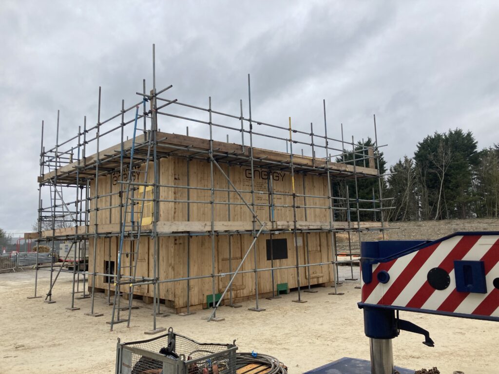 scaffolding surrounding a covered gas compressor on a construction site