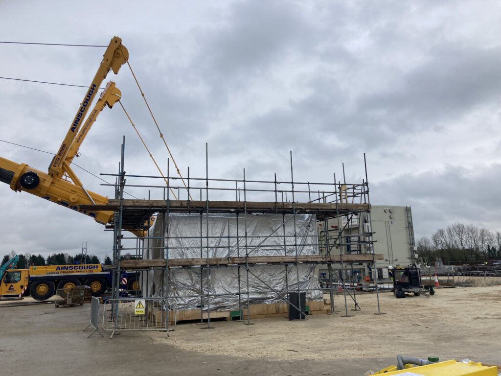 scaffolding surrounding a covered gas compressor on a construction site