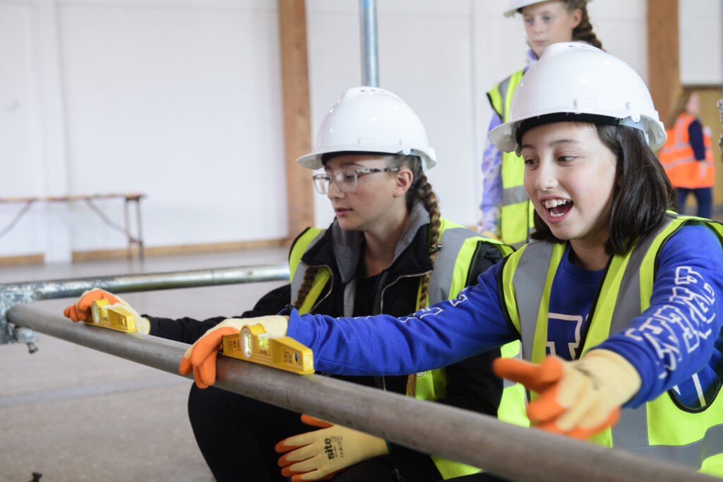 Kids learning how to erect scaffolding equipment