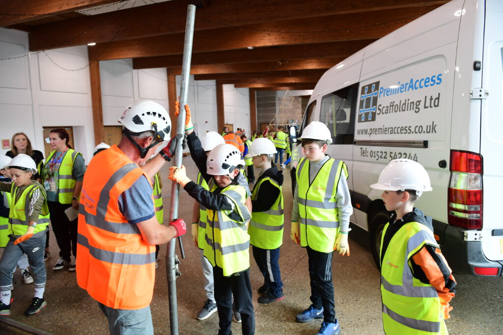 Kids learning how to erect scaffolding equipment